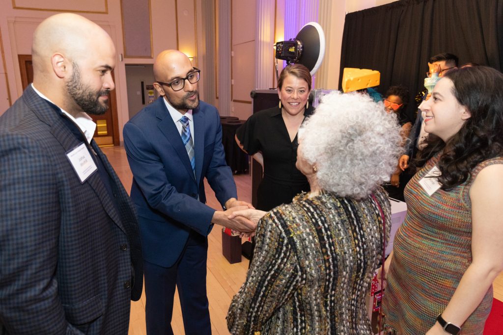 Picture of people talking and a man shaking a womans hand