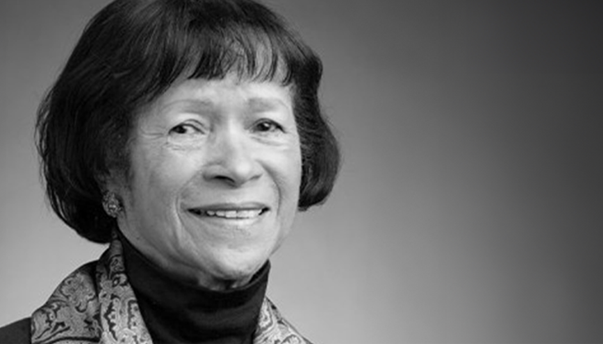 Dr. Mercile J. Lee wearing a dark turtleneck and smiling in a black and white photograph.