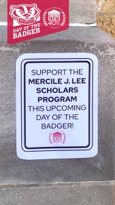 White sign on cement wall saying "Support the Mercile J. Lee Scholars Program This Upcoming Day of the Badger!"